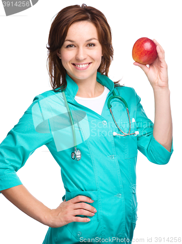 Image of Young lady doctor is holding a red apple