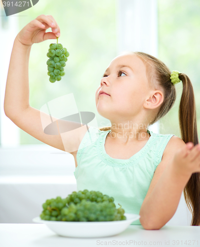 Image of Cute little girl is eating green grapes