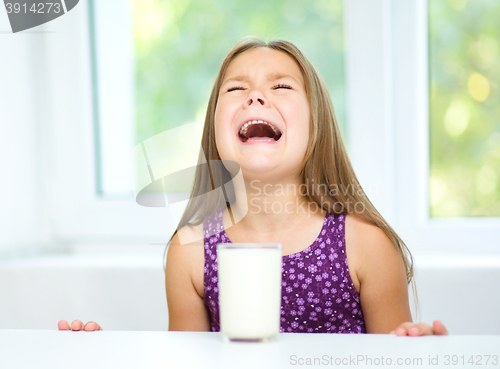 Image of Sad little girl with a glass of milk