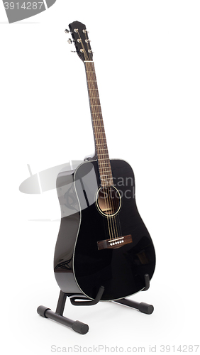 Image of Black acoustic guitar on stand, isolated