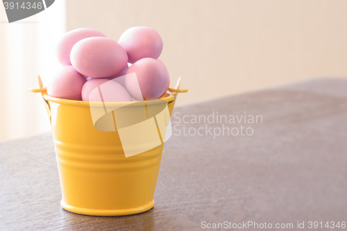 Image of Yellow bucket with violet easter eggs