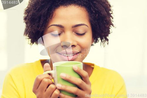 Image of happy african american woman drinking from tea cup