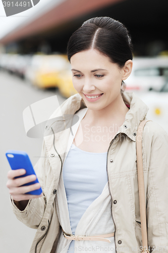 Image of smiling woman with smartphone over taxi in city