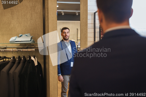 Image of man trying jacket on at mirror in clothing store