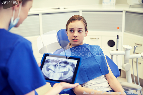 Image of dentist showing x-ray on tablet pc to patient girl