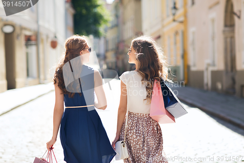 Image of happy women with shopping bags walking in city 