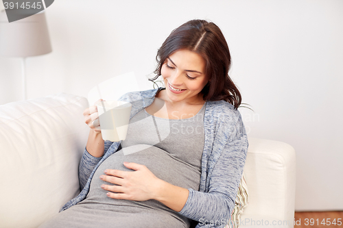 Image of happy pregnant woman with cup drinking tea at home