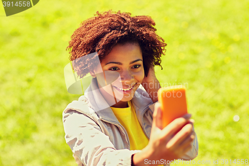 Image of happy african woman taking selfie with smartphone
