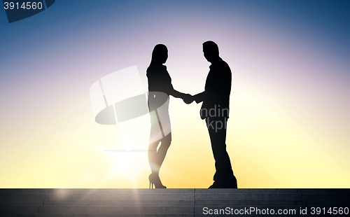 Image of business partners silhouettes shaking hands