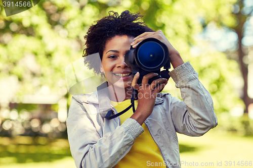 Image of happy african woman with digital camera in park