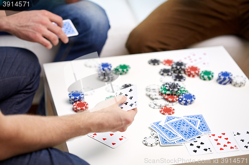 Image of close up of male friends playing cards at home