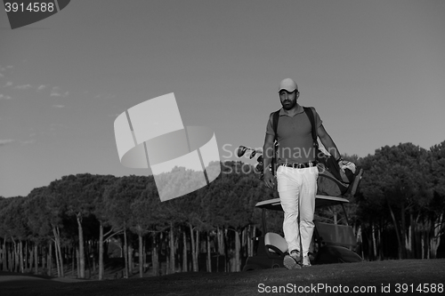 Image of golfer  walking and carrying golf  bag