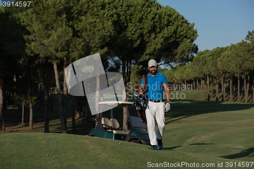 Image of golfer  walking and carrying golf  bag