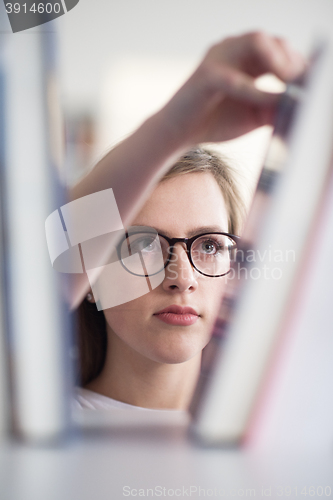 Image of portrait of famale student selecting book to read in library