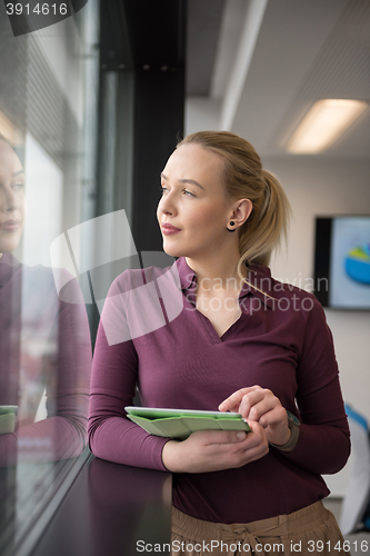 Image of blonde businesswoman working on tablet at office