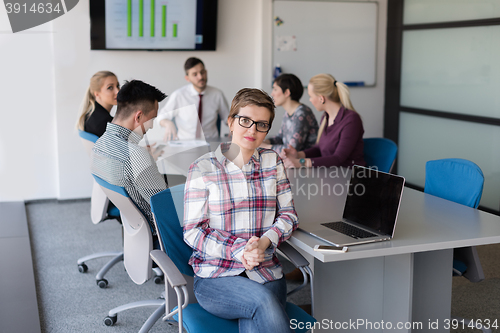 Image of young business woman at office working on laptop with team on me