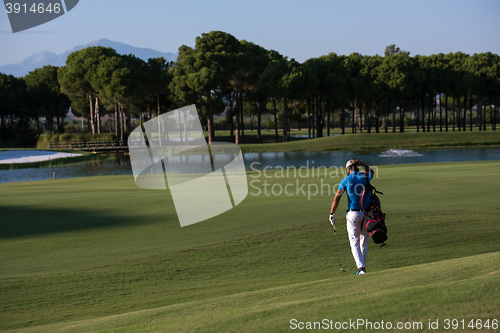 Image of golfer  walking and carrying bag