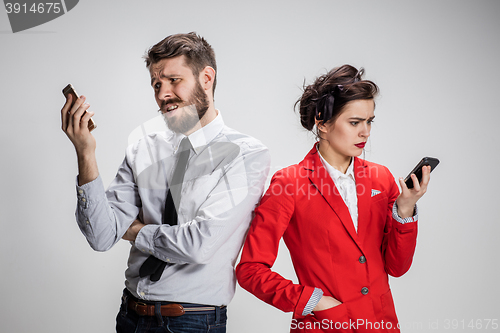 Image of Business concept. The two young colleagues holding mobile phones on gray background