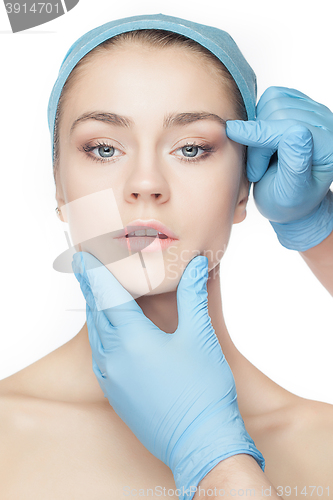 Image of Plastic surgery concept. Doctor hands in gloves touching woman face