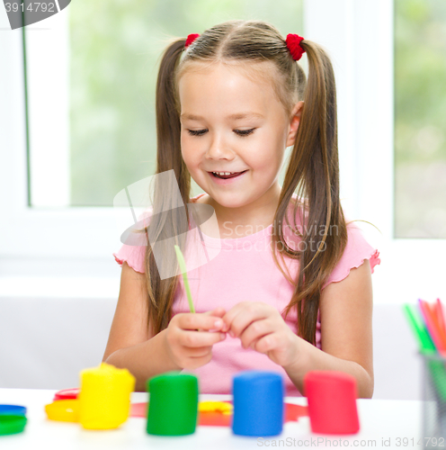 Image of Little girl is playing with plasticine