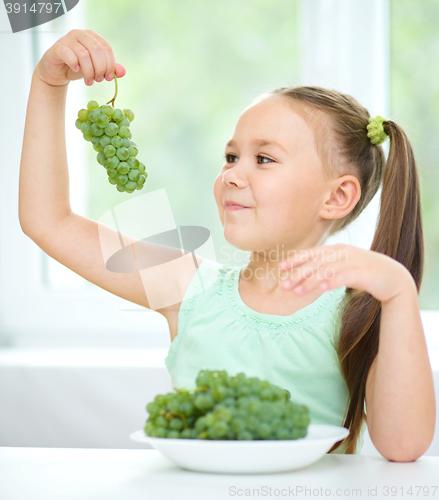 Image of Cute little girl is eating green grapes