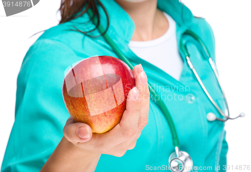 Image of Lady doctor is holding a red apple