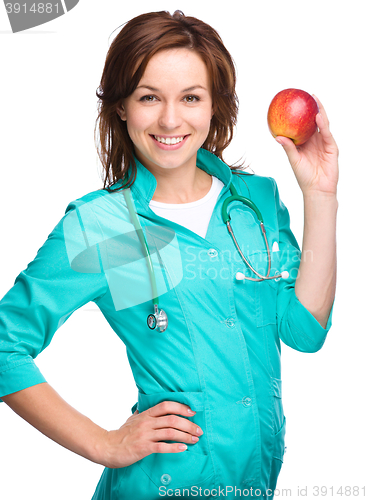 Image of Young lady doctor is holding a red apple