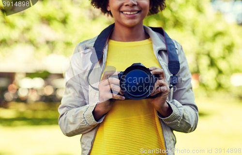 Image of happy african woman with digital camera in park