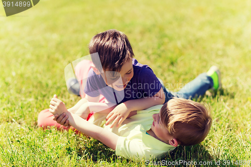 Image of happy little boys fighting for fun on grass