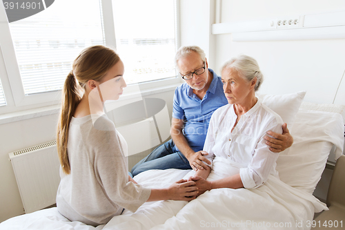 Image of family visiting ill senior woman at hospital