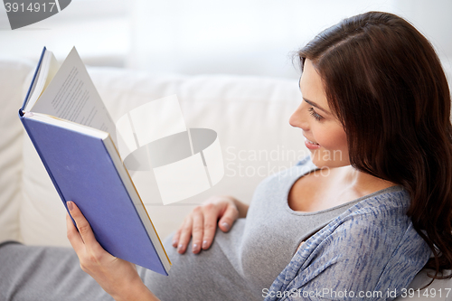 Image of happy pregnant woman reading book at home