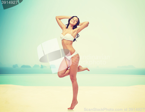Image of happy young woman in white bikini swimsuit