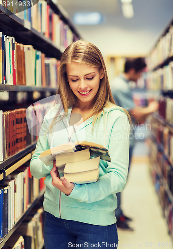 Image of happy student girl or woman with book in library