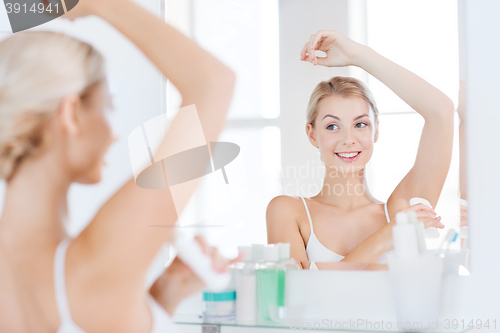 Image of woman with antiperspirant deodorant at bathroom