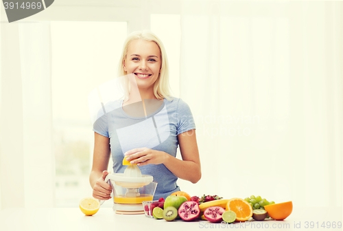 Image of smiling woman squeezing fruit juice at home