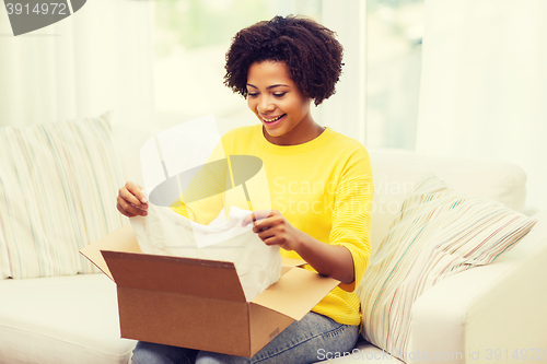 Image of happy african young woman with parcel box at home