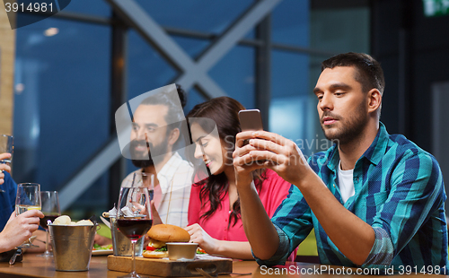 Image of man with smartphone and friends at restaurant