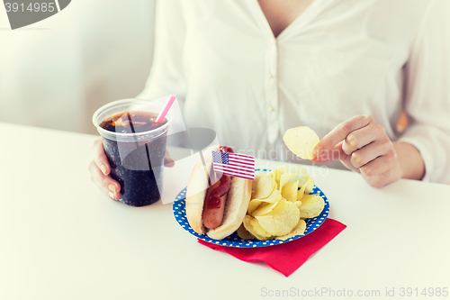 Image of close up of woman eating chips, hot dog and cola