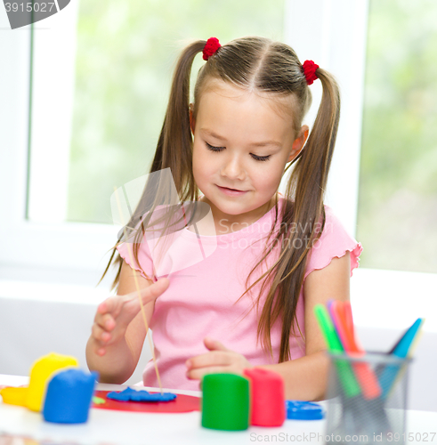 Image of Little girl is playing with plasticine