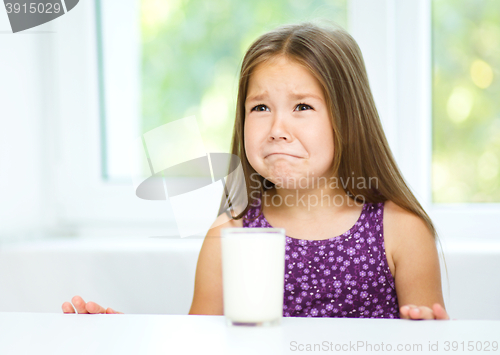 Image of Sad little girl with a glass of milk