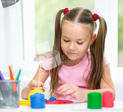 Image of Little girl is playing with plasticine