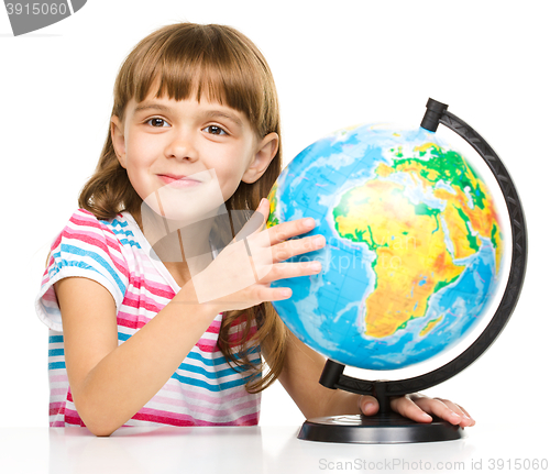 Image of Little girl is examining globe