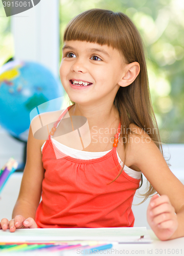 Image of Little girl is drawing using pencils
