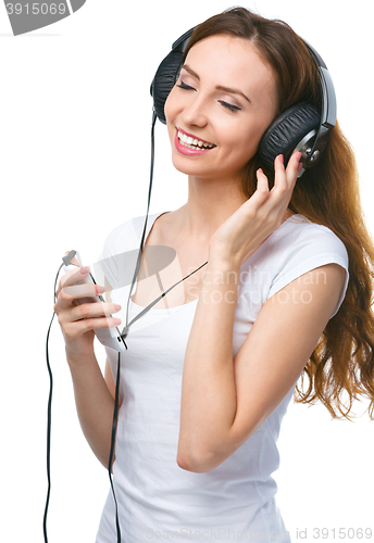 Image of Young woman enjoying music using headphones