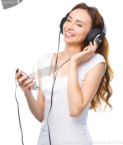 Image of Young woman enjoying music using headphones