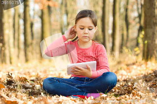 Image of Little girl is reading a book outdoors