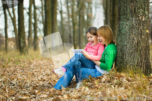 Image of Mother and her daughter is playing with tablet