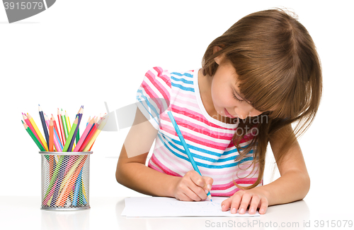 Image of Little girl is drawing using pencils