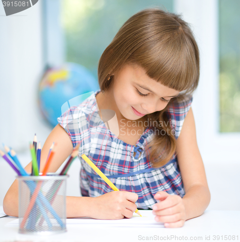 Image of Little girl is drawing using pencils