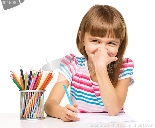 Image of Little girl is drawing using pencils